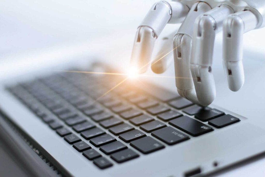 A typical bad stockphoto of AI showing a robotic hand typing on a computer keyboard