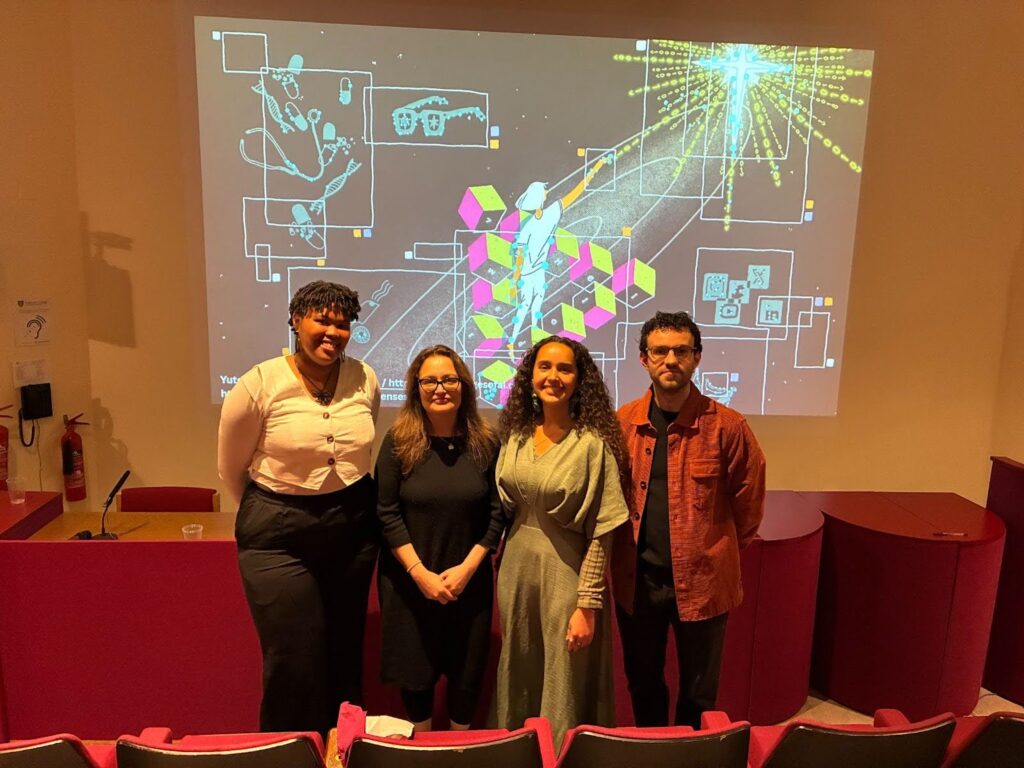 Chanelle, Tania, Hannah, and Alex stood smiling in front of a projected image of Yutong Liu's image "AI is Everywhere". 
