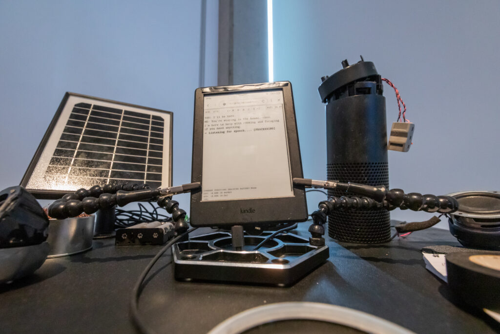 An Amazon kindle surrounded by other technology hardware and wires