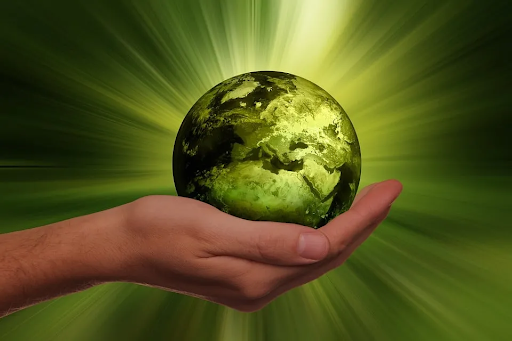 On a green background, a the palm of a hand cups a green globe. God-like, holy radiance emanates from the globe through a glowing effect.